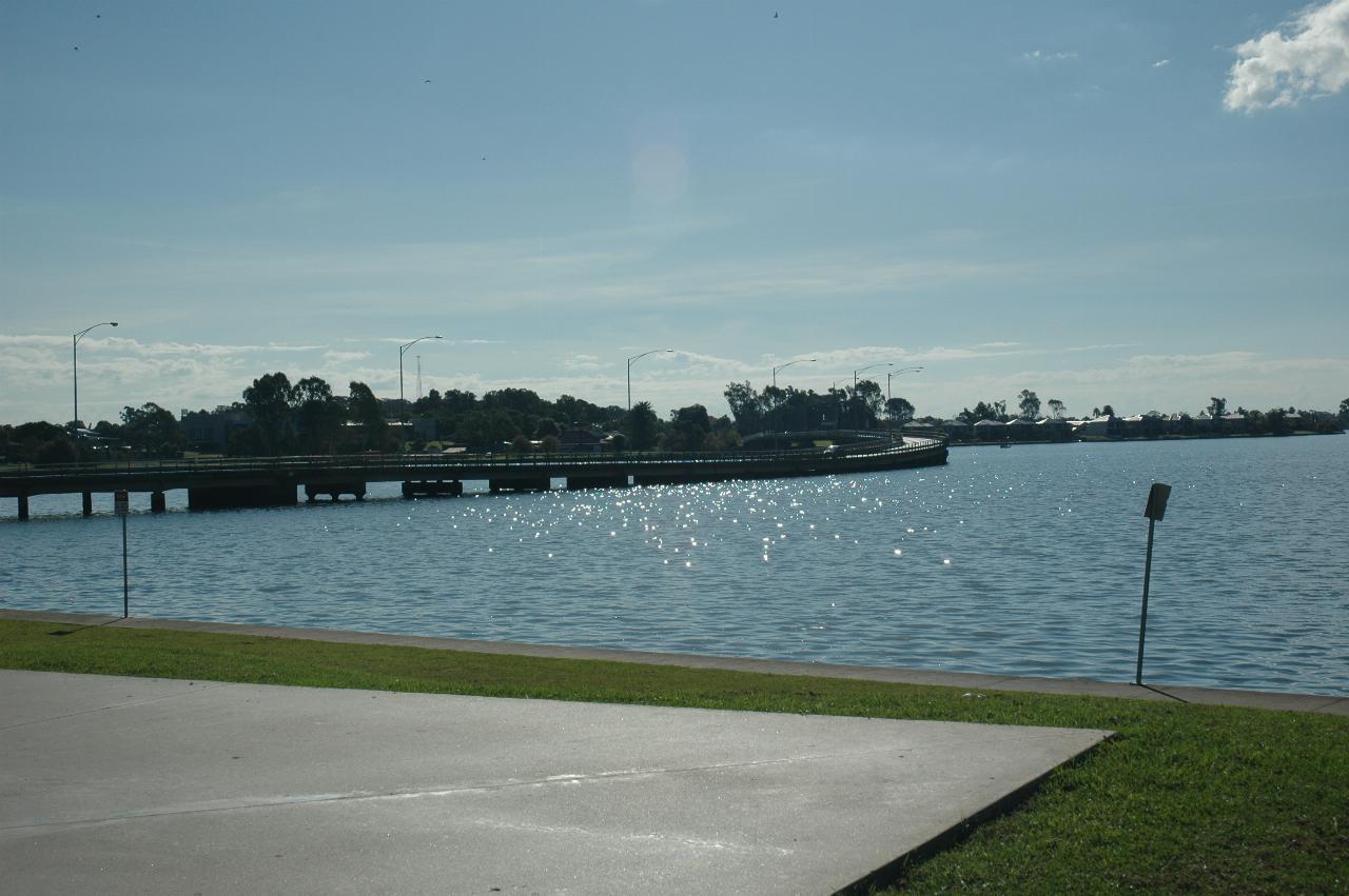 Road bridge across the lake, close to surface, trees and homes beyond