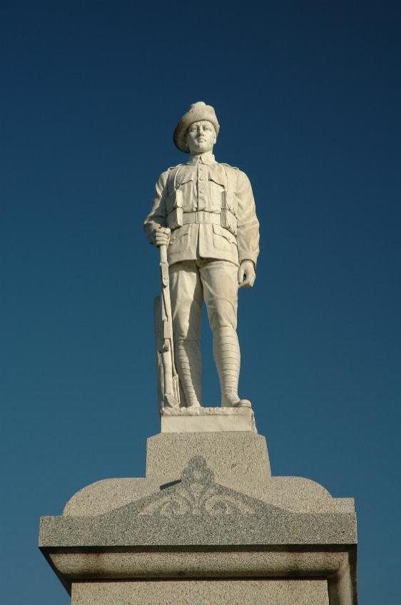 Statue of a soldier, standing, holding gun with butt resting on ground