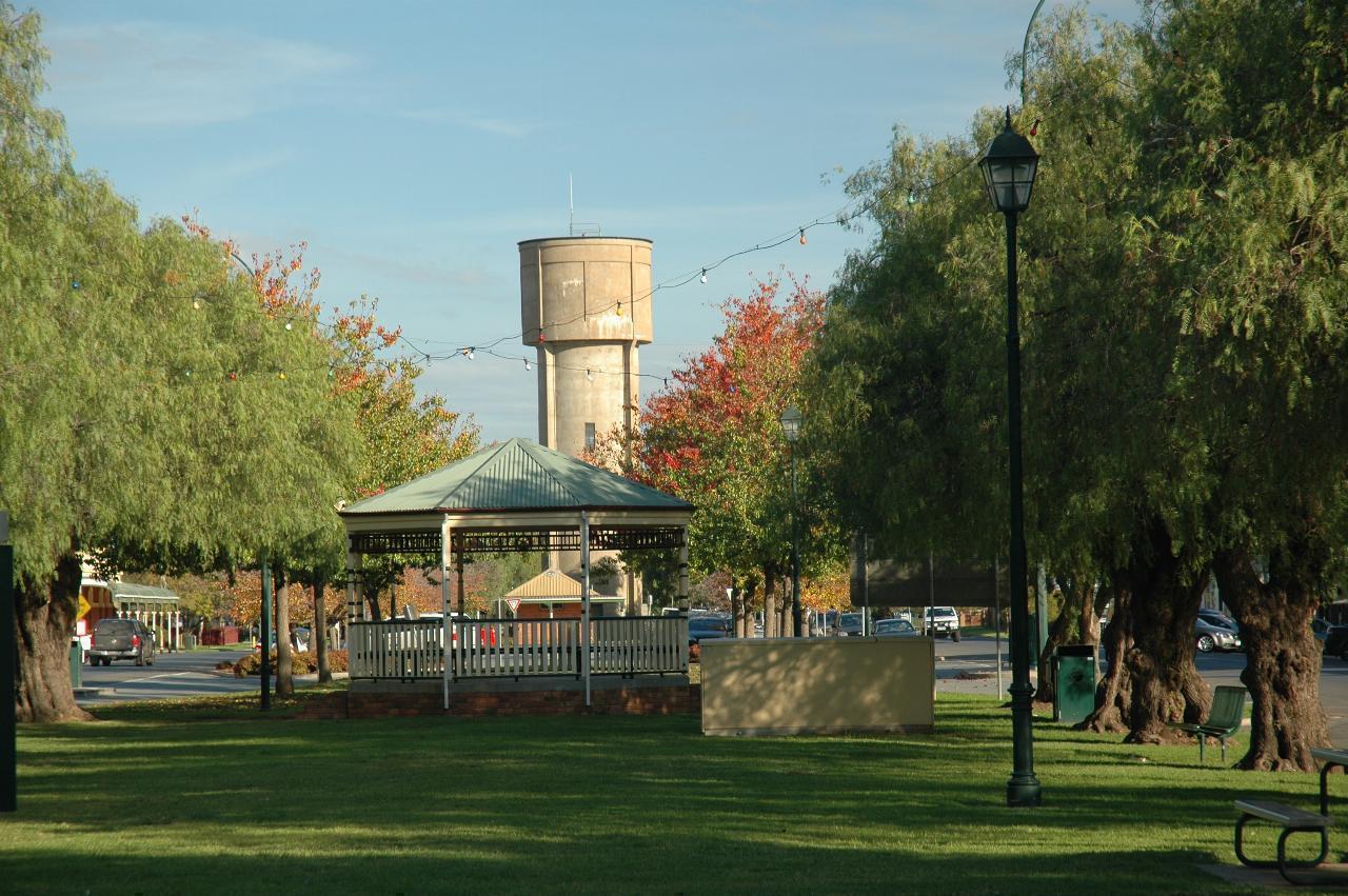Grassy area with trees along the edge, towards rotunda and town water tank behind
