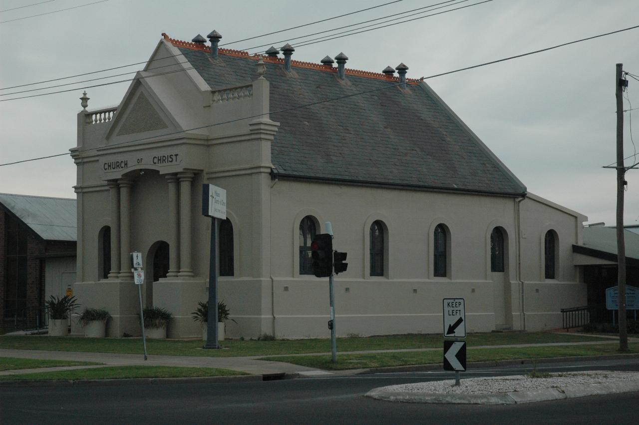 Drab gray church with black window frames and dark grey roof; no tower or spire