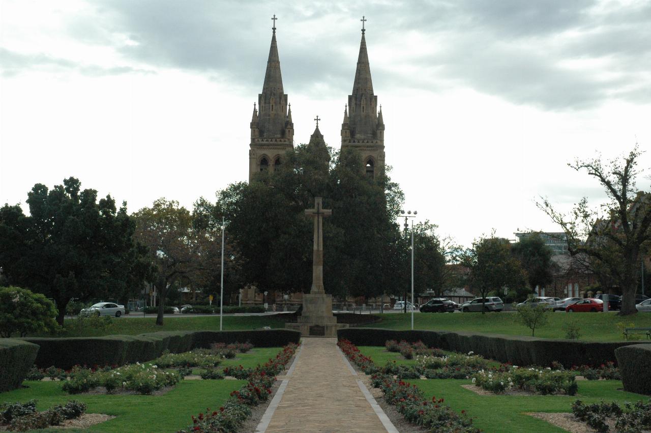 Lightly enclosed garden, path leading to cross, and twin towers of cathedral further back