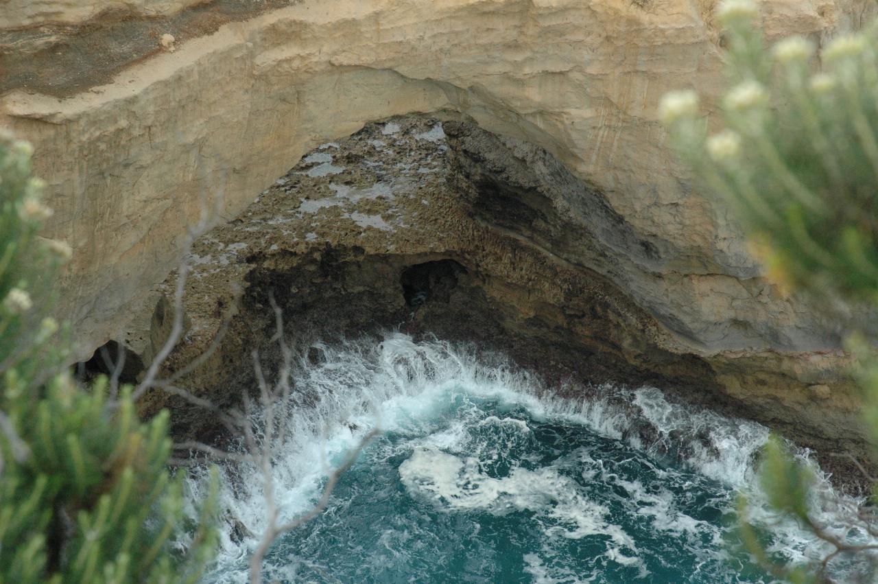 Lower part of natural arch, showing water retreating from rock platform beneath as wave returns to ocean