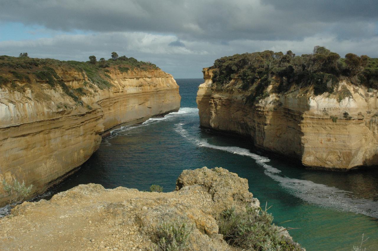 Long narrow gorge, ochre coloured cliffs with vegetation on top, ocean coming in
