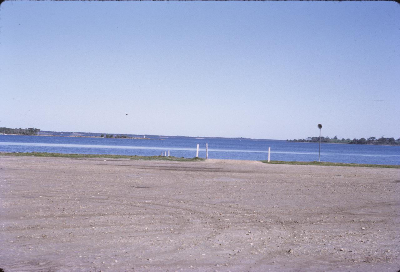 Dirt parking lot, boat ramp, and water off to the horizon