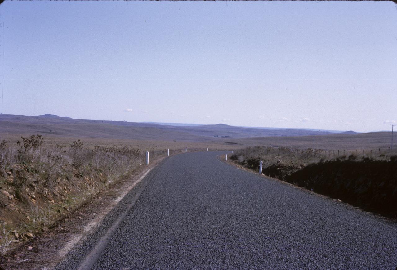  Newly sealed road in brown pasture, a distant hills