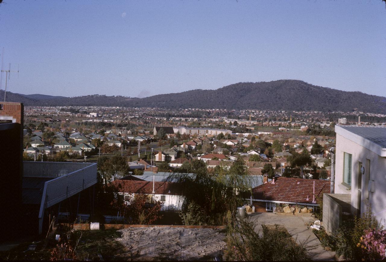 View between houses over many houses to distant hill