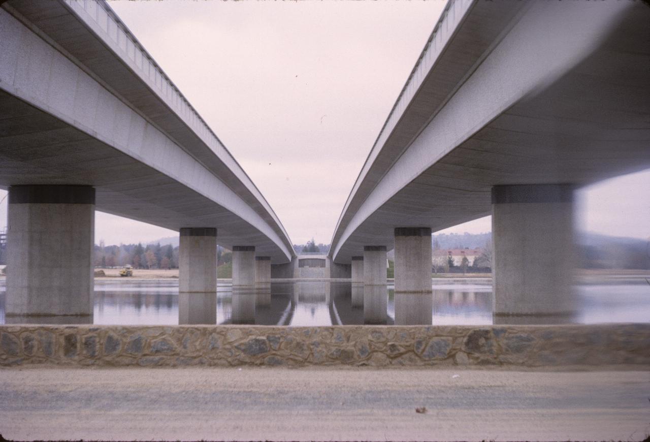 Photo across lake between parallel bridges