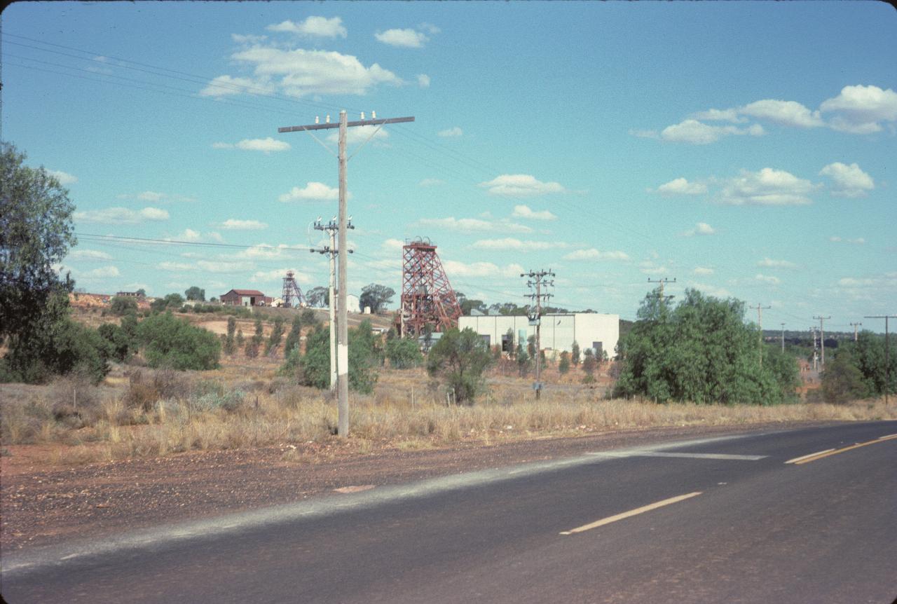 Mine buildings and winding towers near the road and distant hill