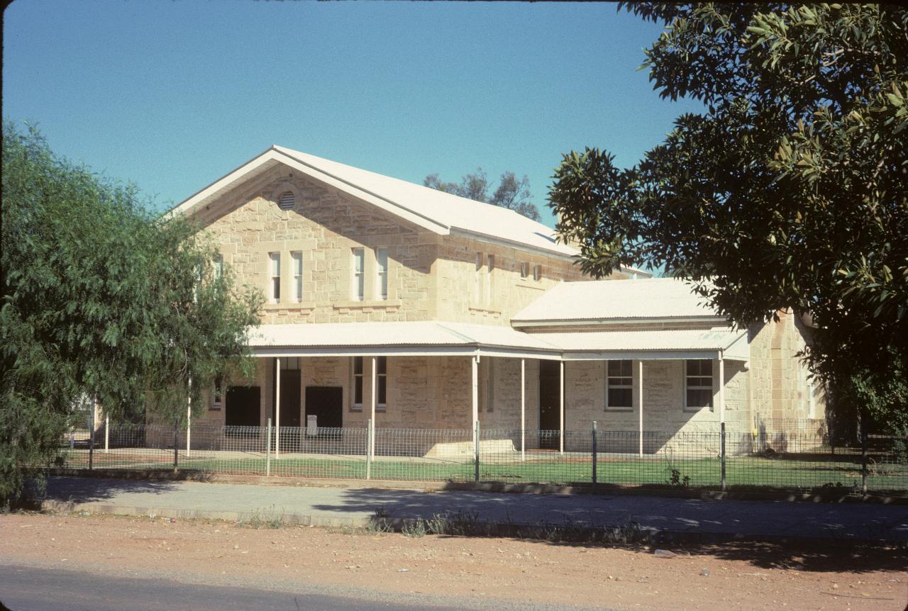 Two storey stone building with white roof, wide verandah