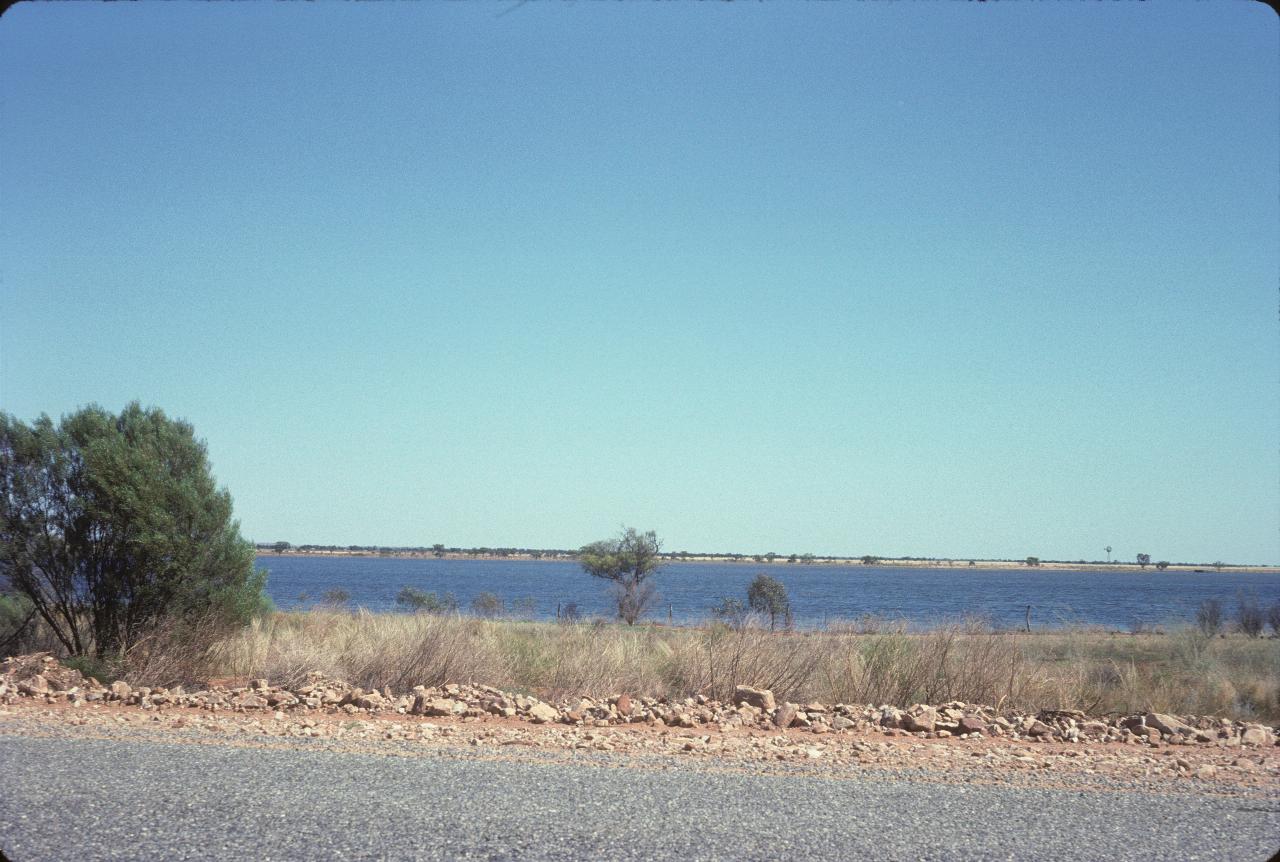 A small lake beside the road; otherwise flat with a little scrub