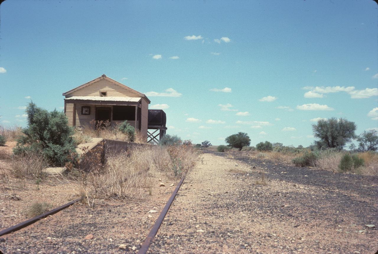 Small building on abandoned platform and rail line, with water tank