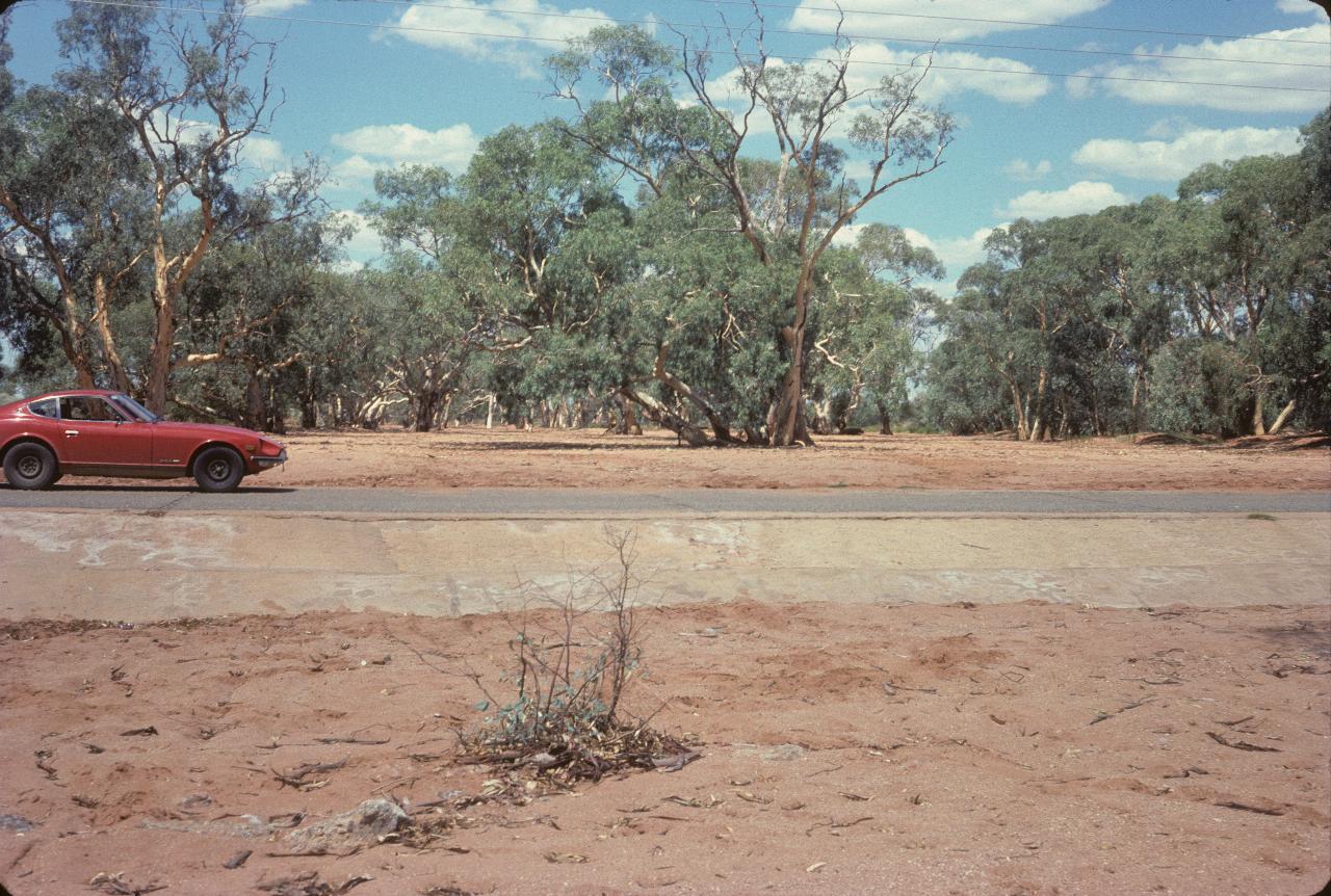 Car parked on roadway crossing a dry river bed