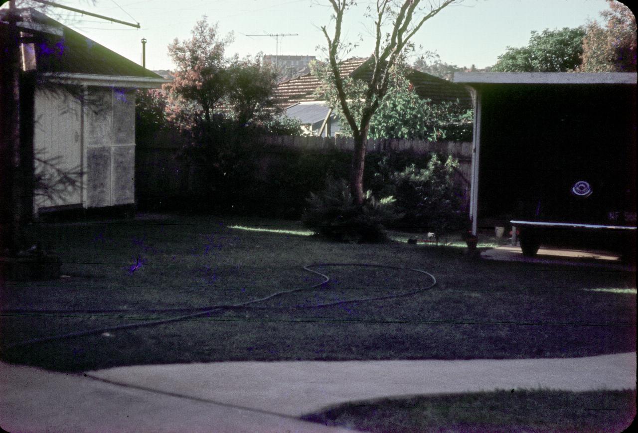 Back yard view with cubby house and car port