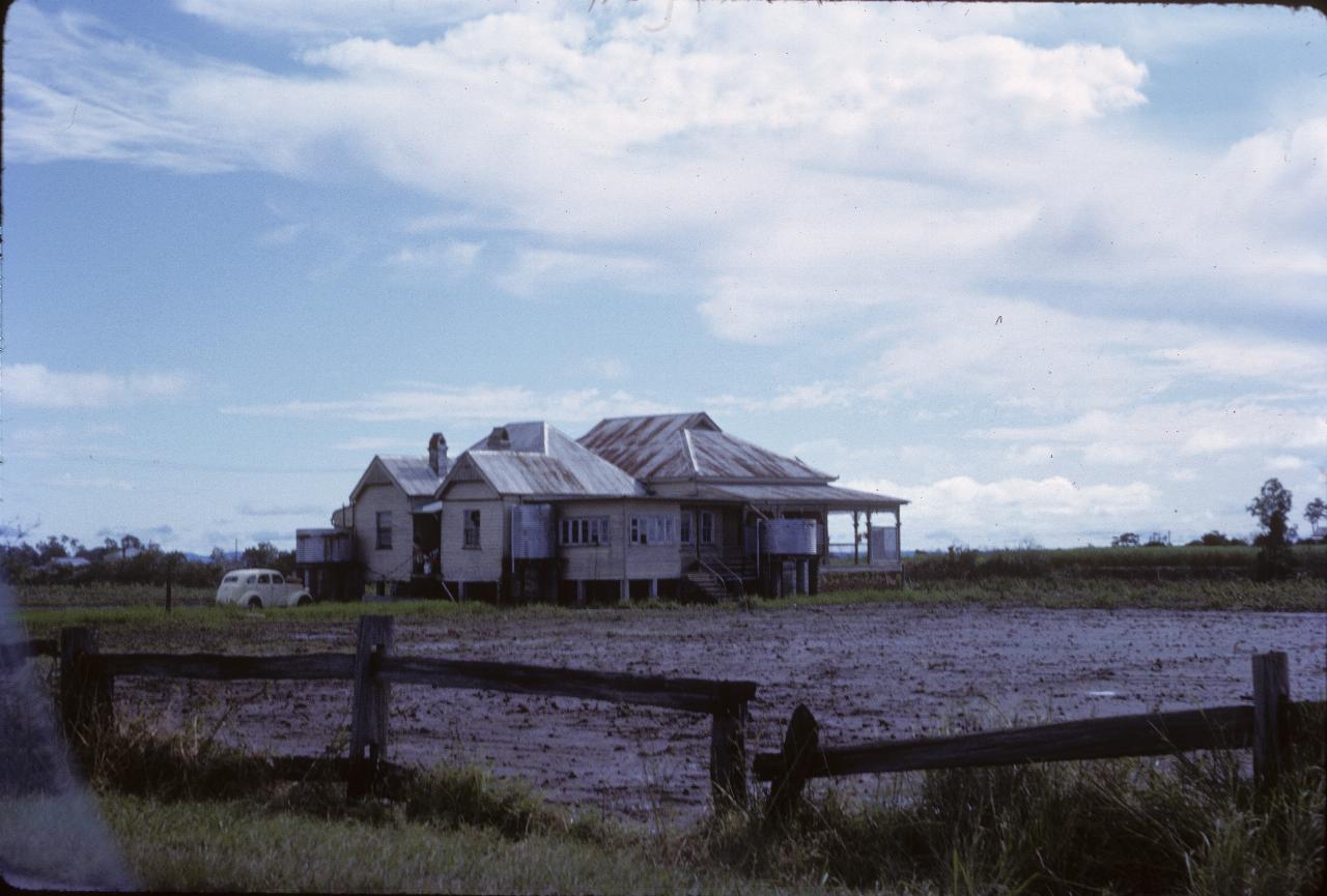 House in need of paint in middle of muddy field