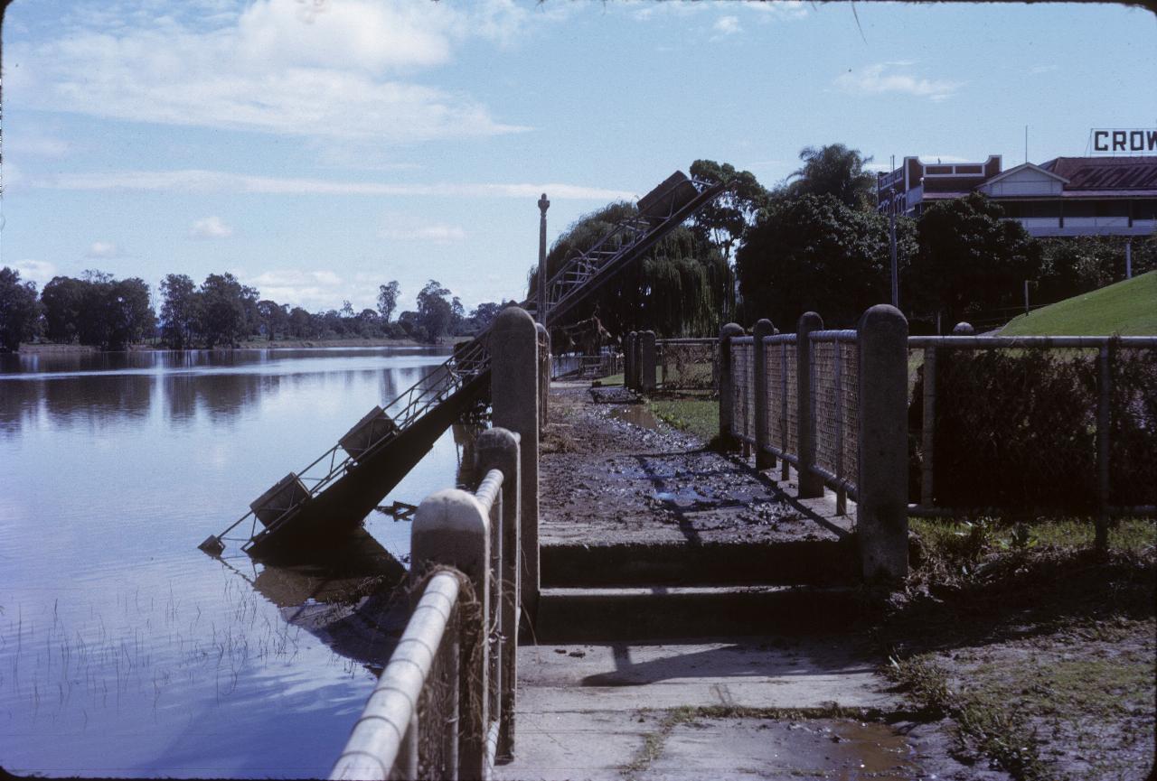 Small river pontoon caught up in riverside fence