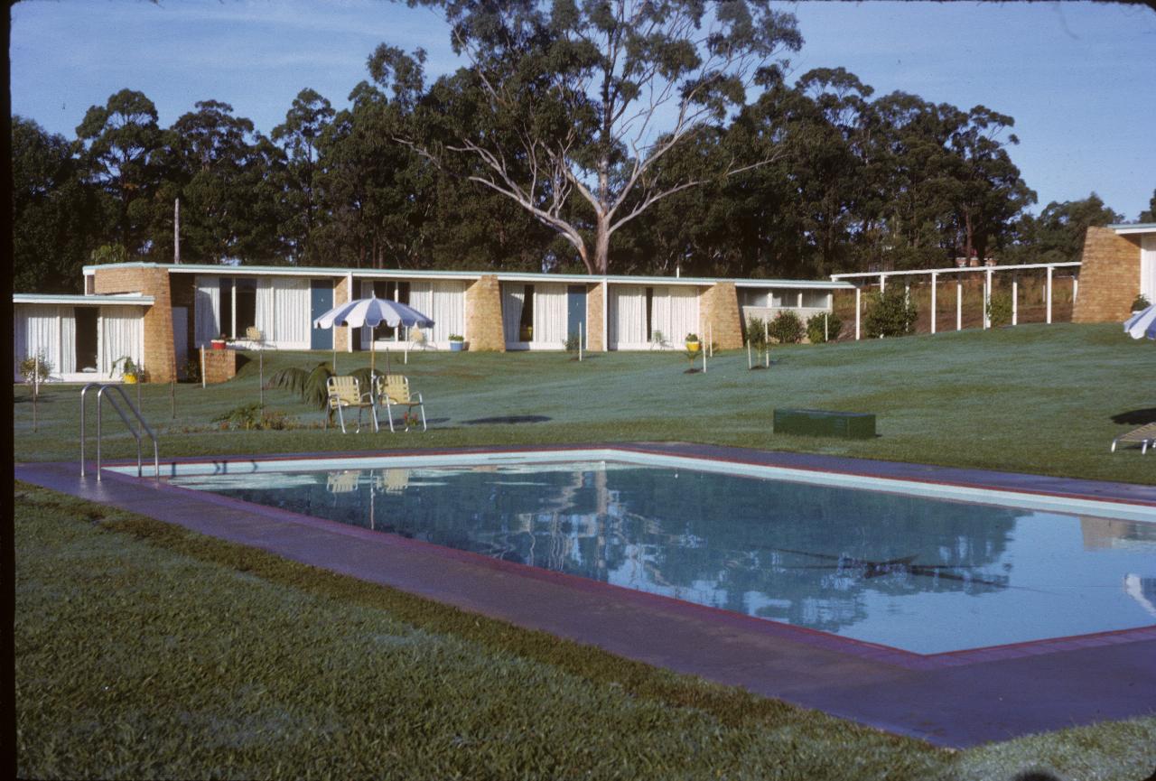 Single story, light coloured brick motel buildings around swimming pool