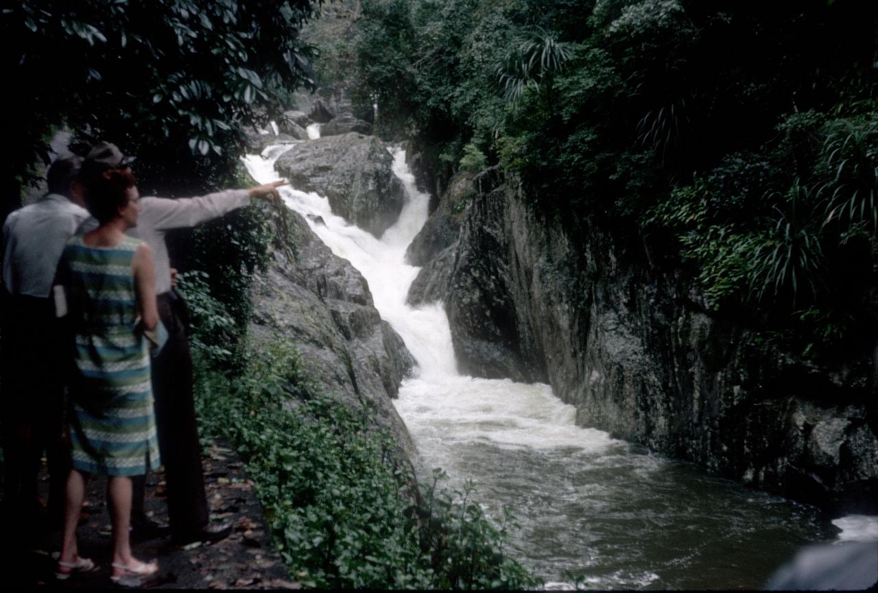 People along path with small falls into narrow stream