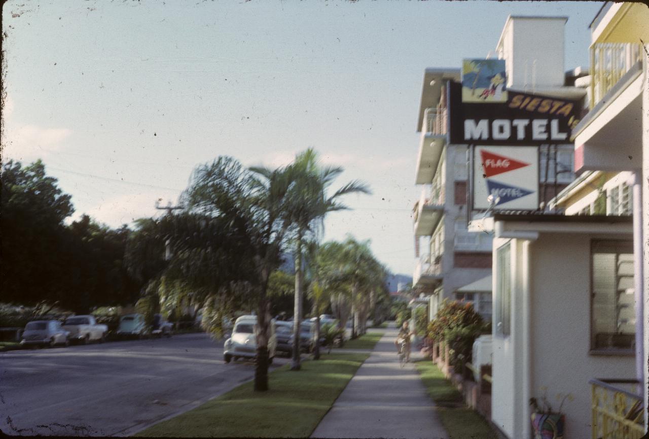 View down street with buildings on right, park on left