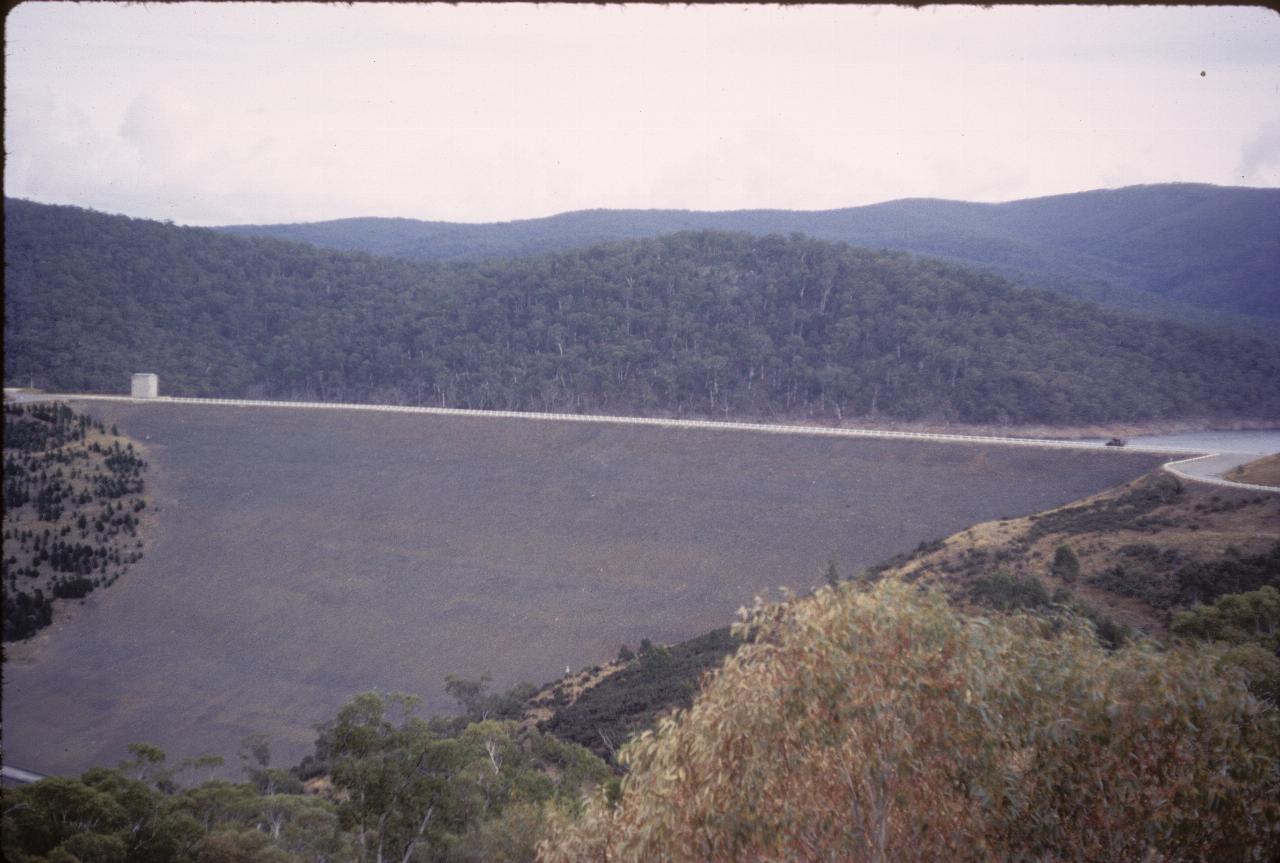 Large earthen dam wall with tiny vehicle on top