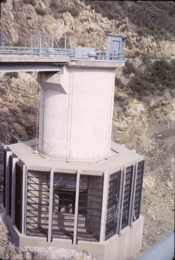 Hexagonal concrete structure with cylindrical upper part in river bed.