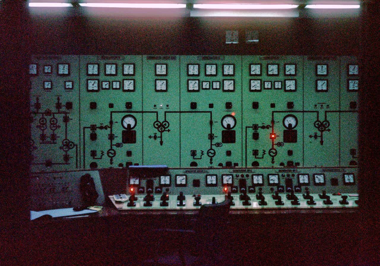 Electrical control room; green panelsat rear with meters; switches on operator panel in foreground