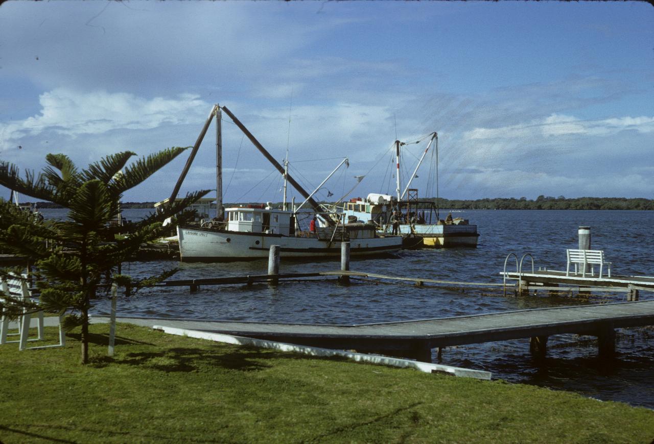 Couple of fishing boats tied up to a wharf on a river