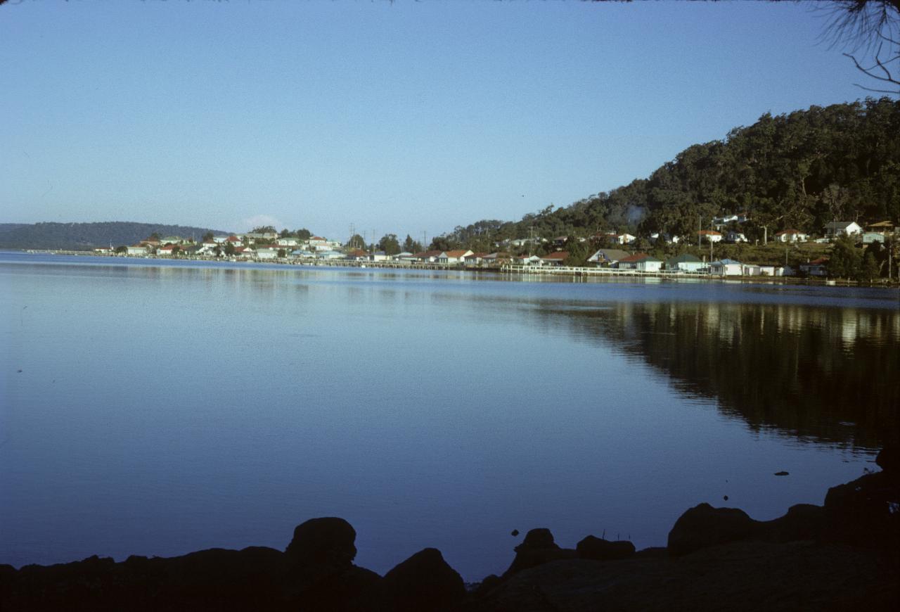 Across calm water to headland with houses along shore