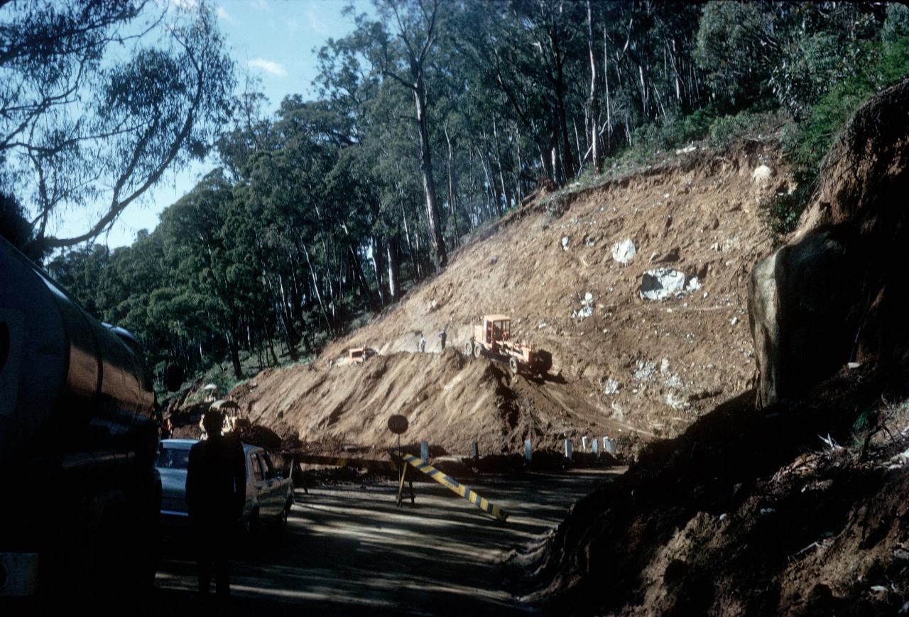 Grader cutting down hill side for road widening