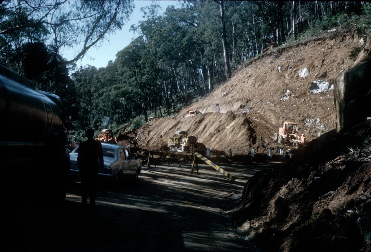 Grader cutting down hill side for road widening