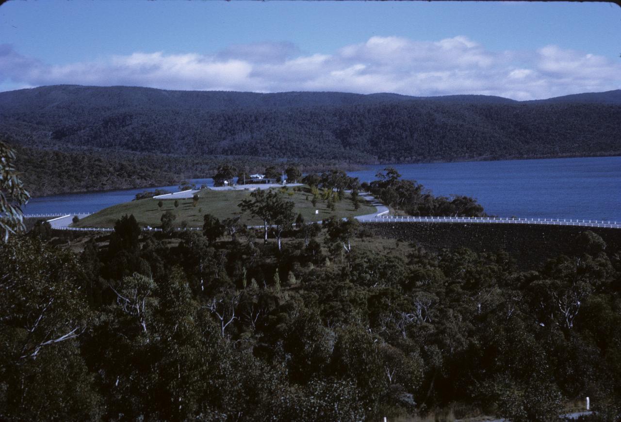 Visitor area on hill between 2 dam walls, with water amid thickly vegetated hills