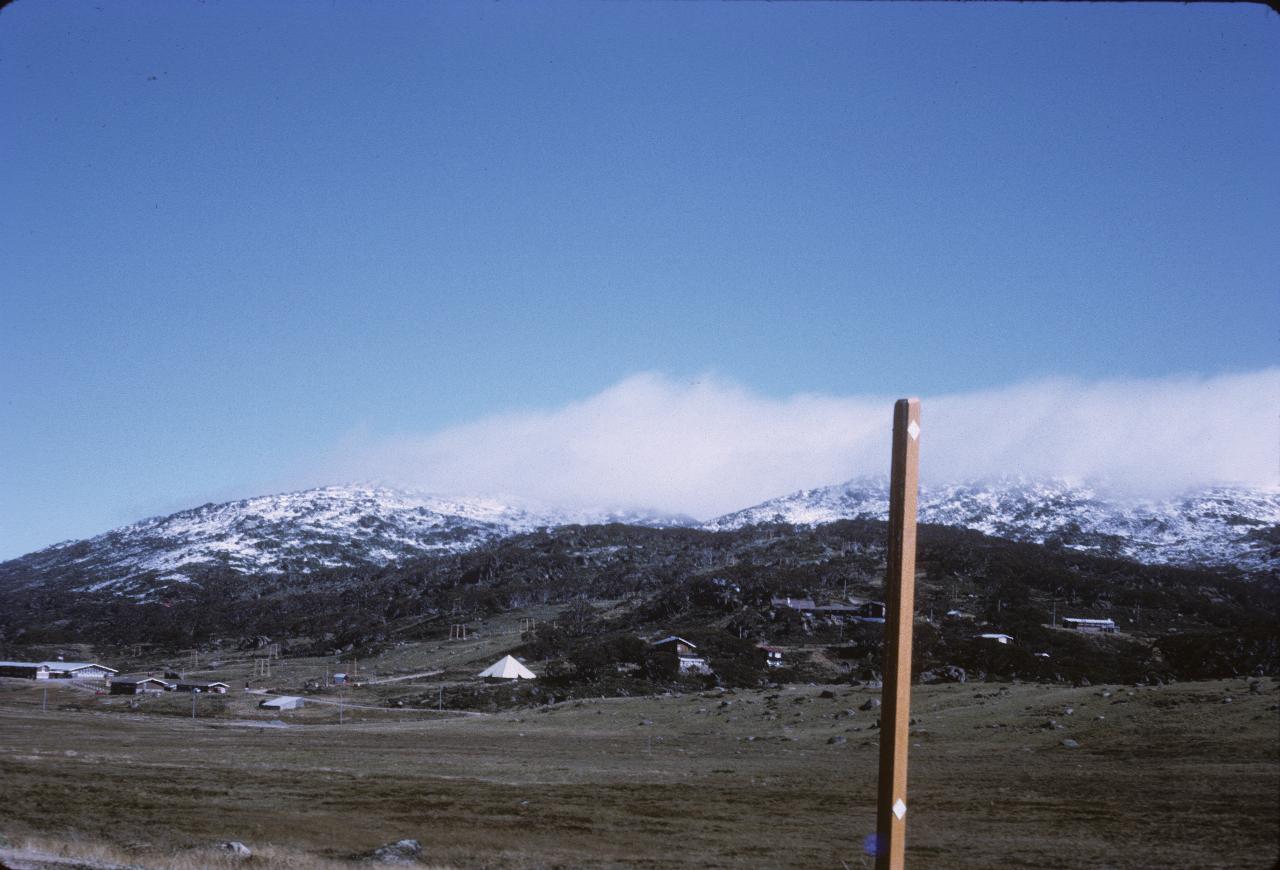 Plane with hills behind and a light snow fall