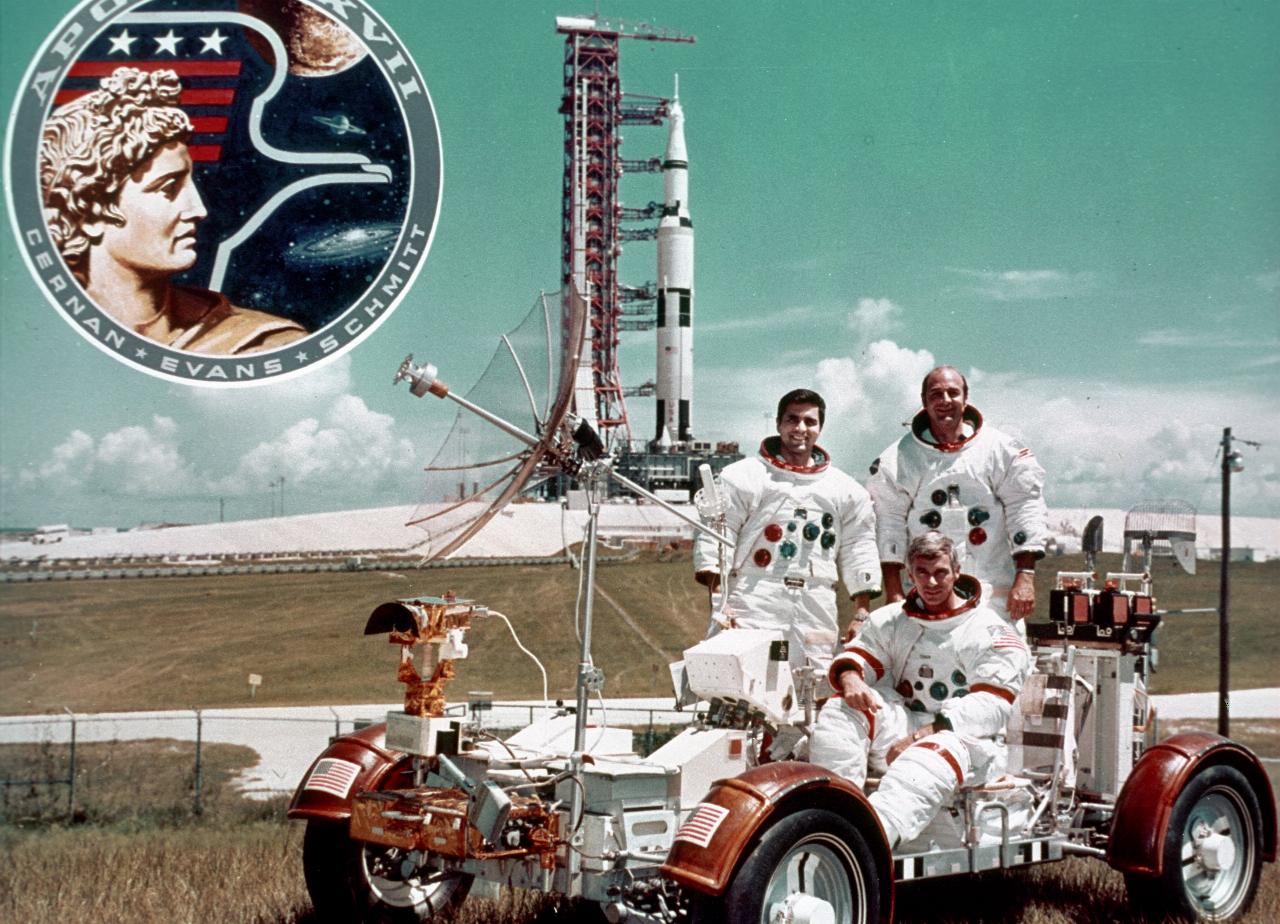 3 men on lunar rover in front of Saturn V rocket