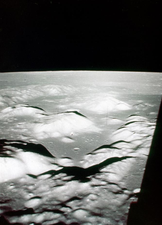 View of gray lunar surface with craters and mounds