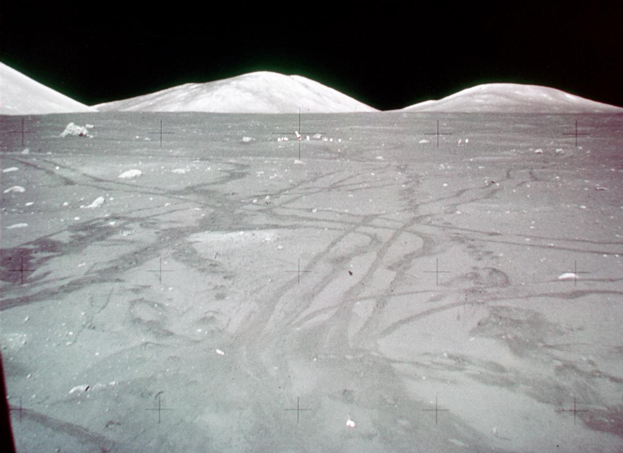 View from lunar module showing tyre tracks of rover, distant low hills