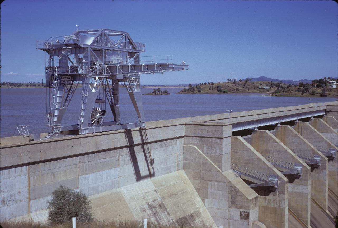 Concrete dam, metal crane on rails on wall and full storage