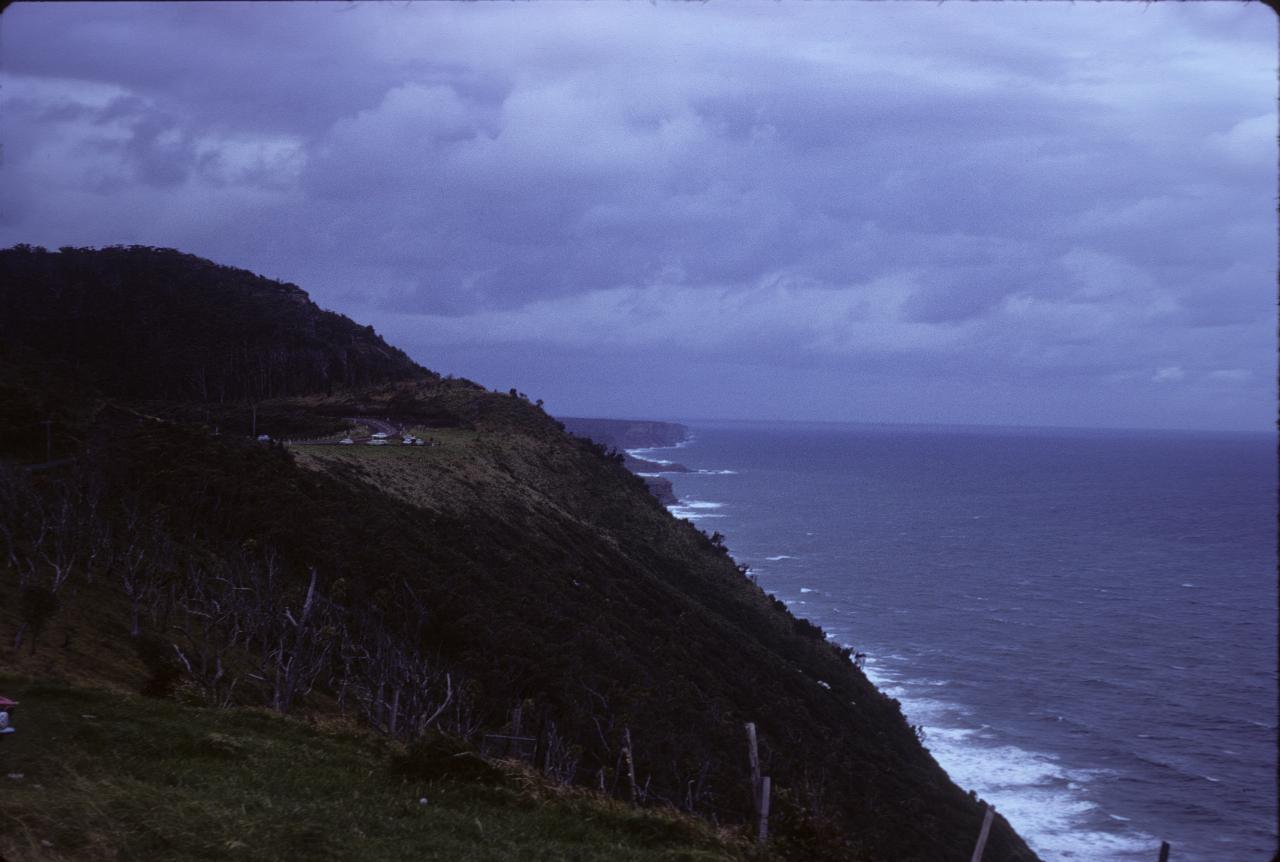 High view along coastline, with breaking waves and dark clouds