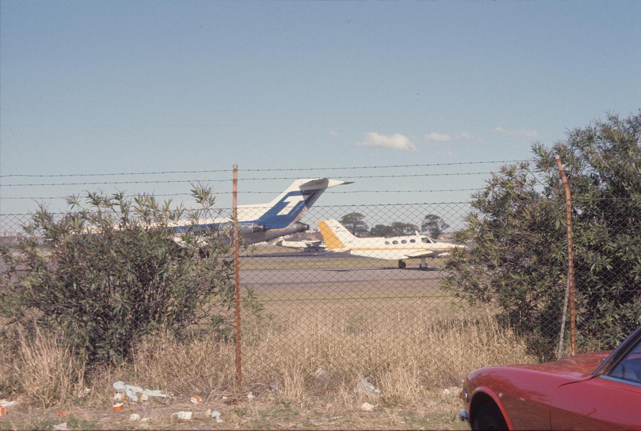 B727 and twin engined light plane behind chain link fence