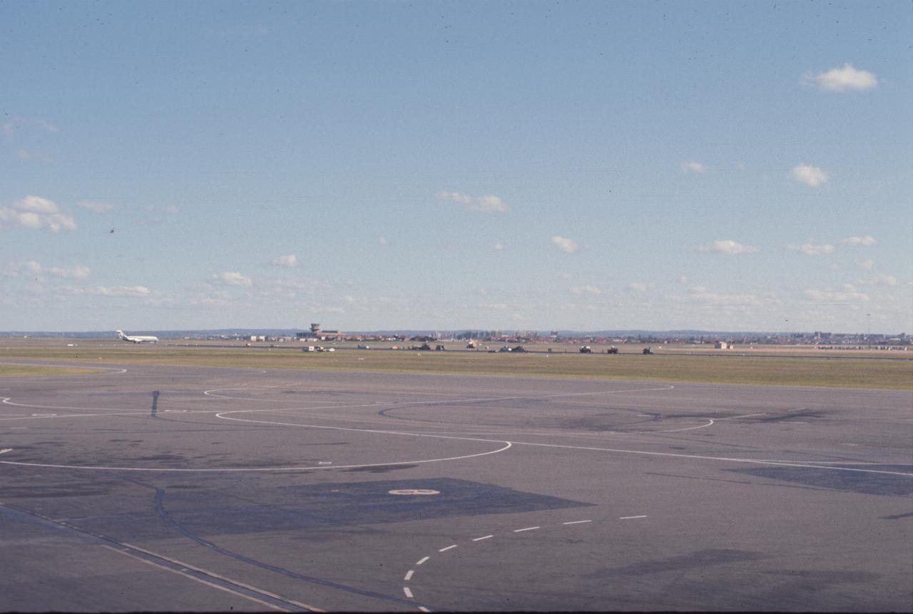 View across airport; plane on runway; distant hills