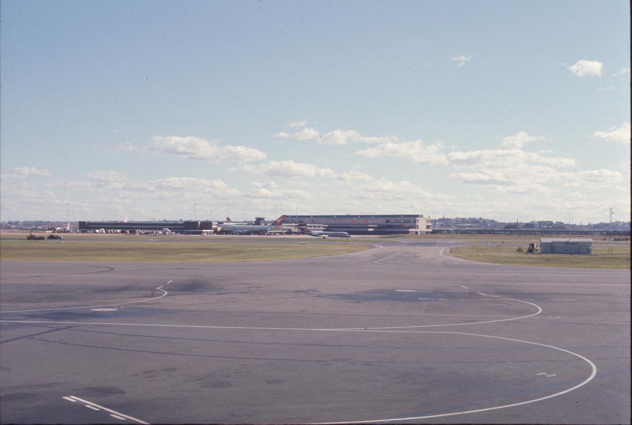 View across airport to terminal with plane waiting and one taxiing