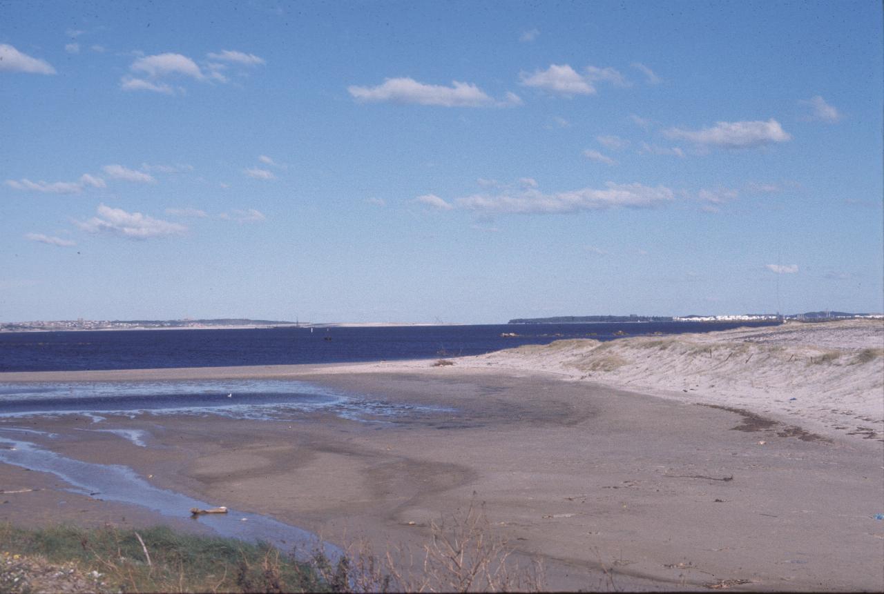 Low tide, looking over water to distant headlands and ocean