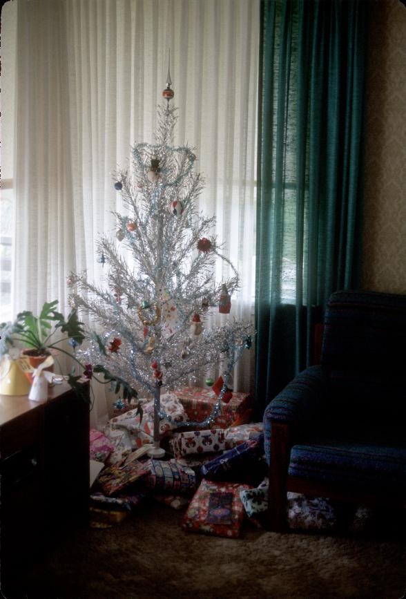 Artificial Christmas tree in corner of room; presents below