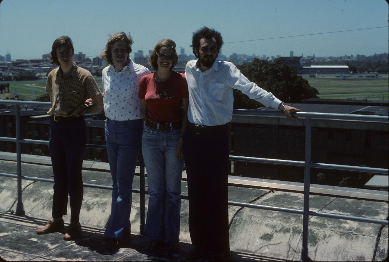 Four people on a roof, race course in the background