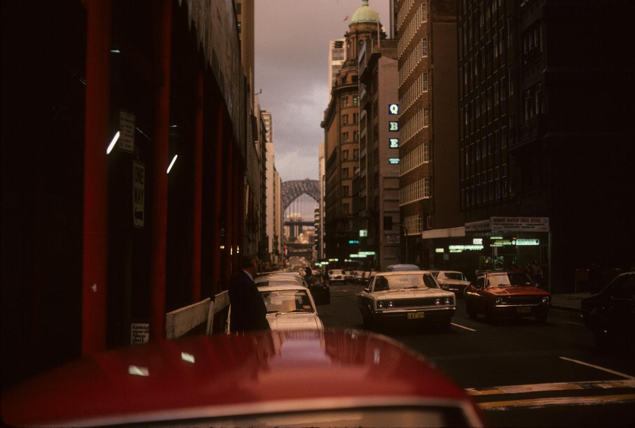 Street with buildings both sides, arch bridge in the distance