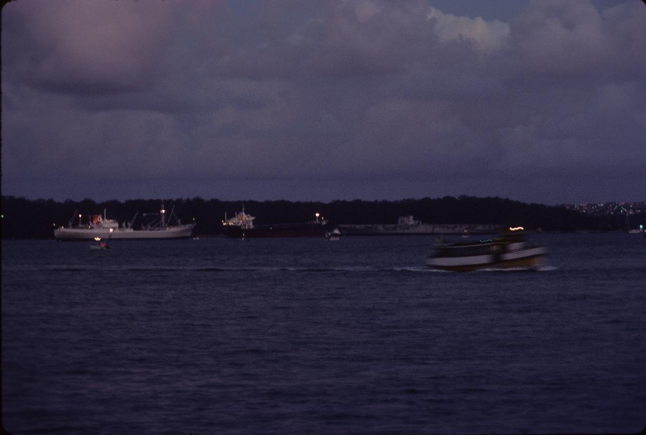 Aircraft carrier and other shipping in harbour at dusk