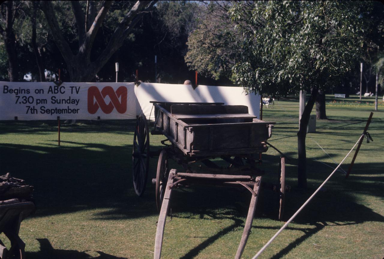 Horse drawn wagon in front of sign advertising TV program