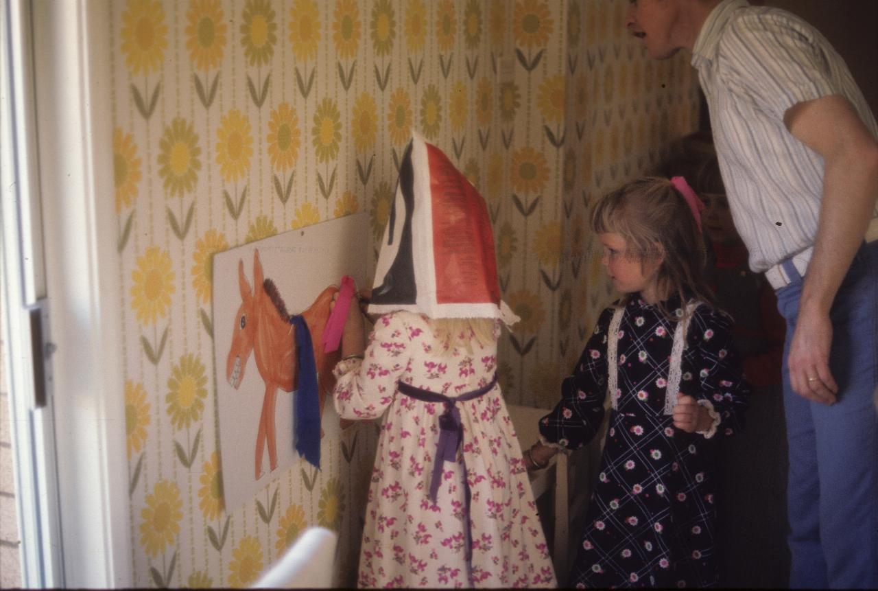 Hooded girl near wall, another little girl and man watching