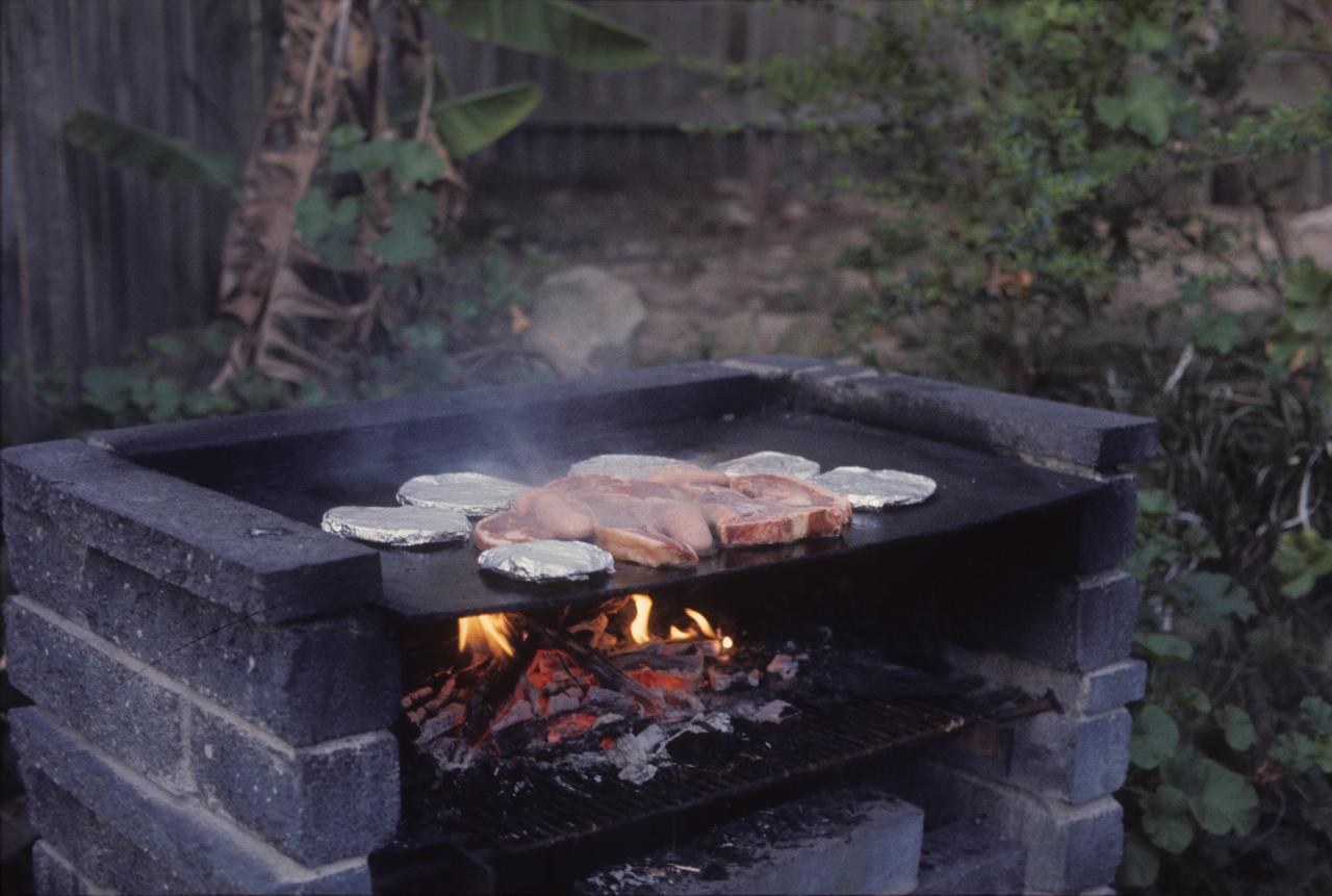 Gray cement block bbq with fire and food cooking