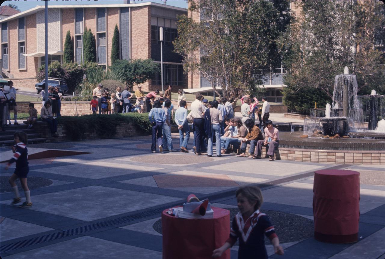 The plaza from ground level, showing ramp and red barrels for an obstacle course