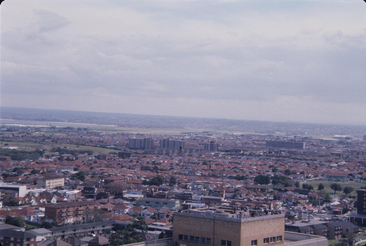 View over buildings, then houses to airport and bay