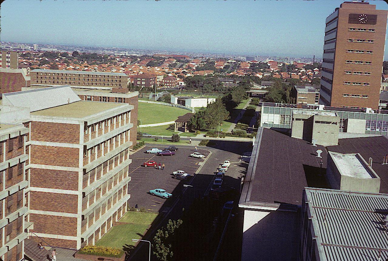 A number of university buildings, oval and across houses to very distant mountains